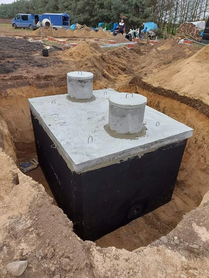 Betonowy zbiornik z dwoma otworami rewizyjnymi w wykopie